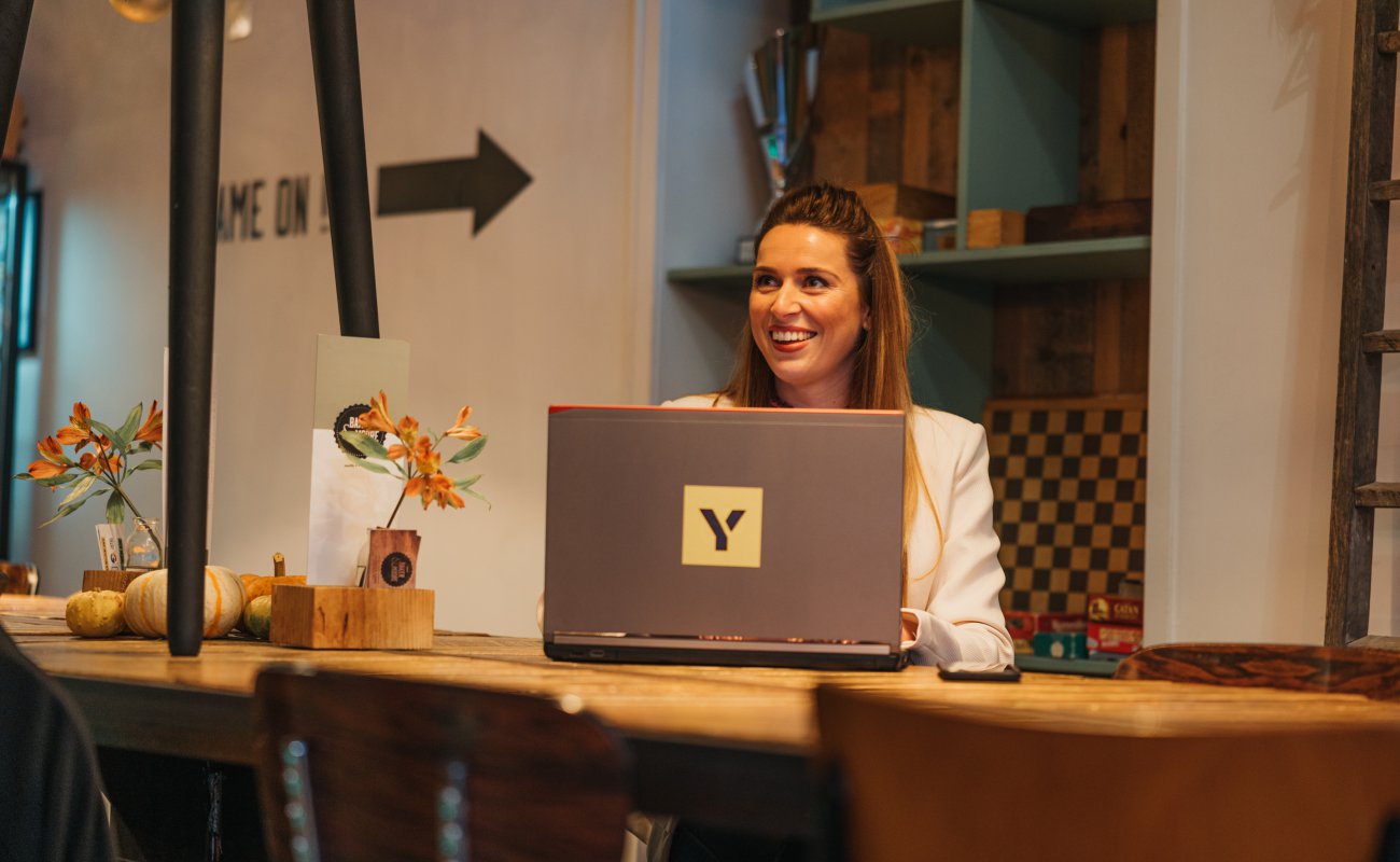 Girl behind laptop smiling looking to colleague