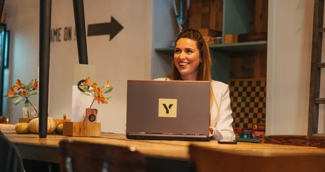 Girl behind laptop smiling looking to colleague